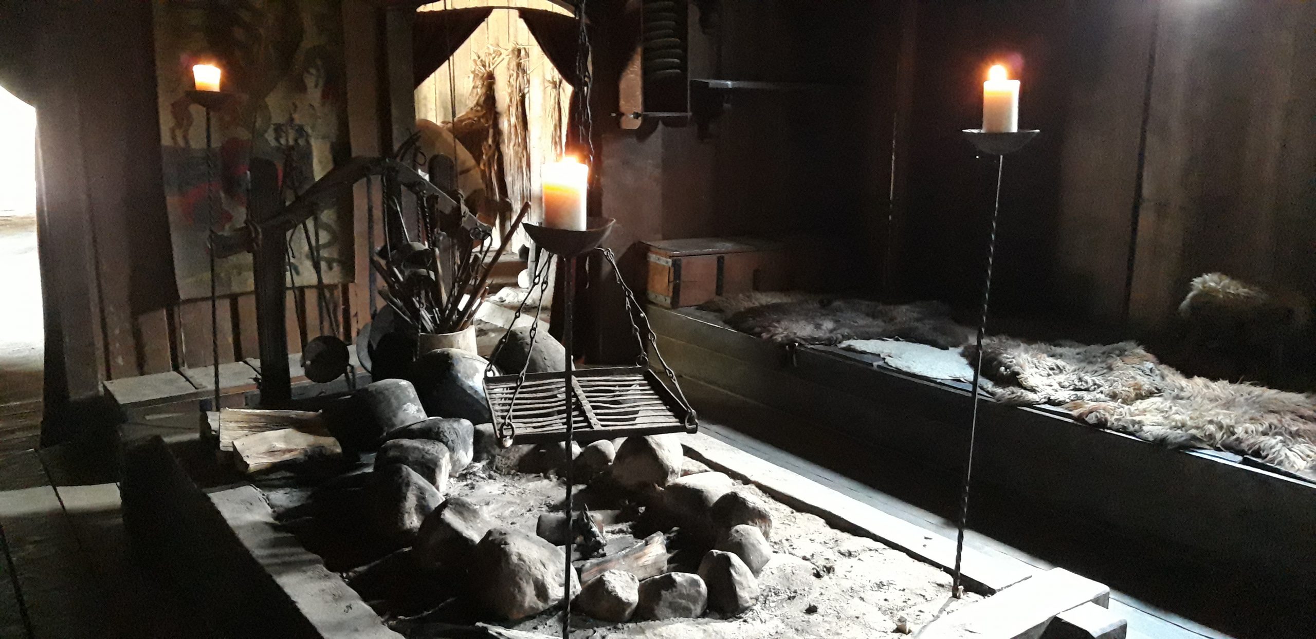 Langhaus eines Wikinger-Gutshofs, an den Seiten Sitz- und Liegeplätze und eine Feuerstelle in der Mitte